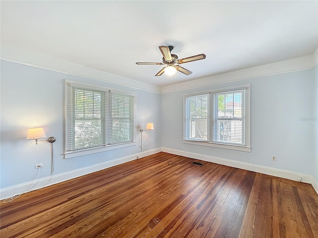 empty room featuring wood-type flooring, baseboards, a ceiling fan, and visible vents