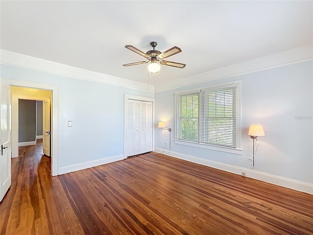 unfurnished bedroom with a closet, dark wood-style flooring, baseboards, and ceiling fan