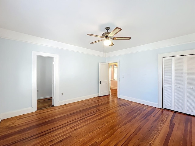unfurnished bedroom featuring baseboards, a closet, hardwood / wood-style floors, and a ceiling fan
