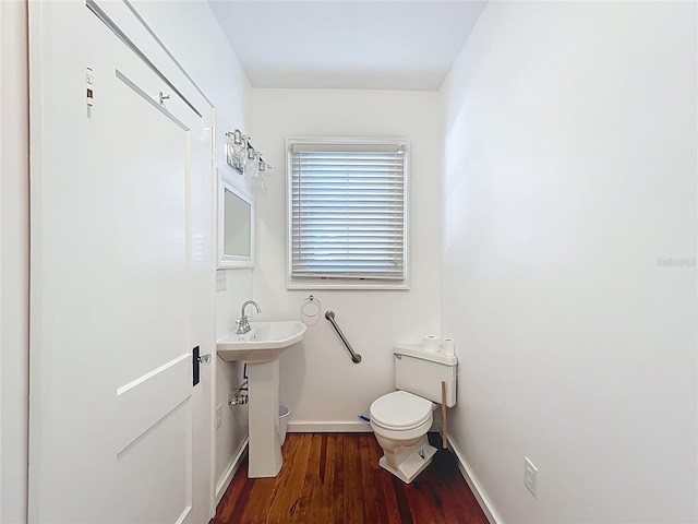 half bathroom featuring toilet, wood finished floors, and baseboards