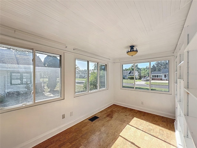 unfurnished sunroom with visible vents, baseboards, and wood finished floors