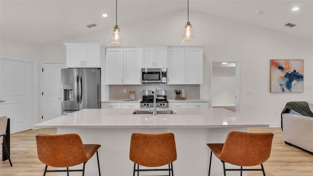 803 Allison Pl, Bartow, FL 33830 - kitchen with appliances with stainless steel finishes, light wood-style floors, white cabinetry, a breakfast bar, and high vaulted ceiling