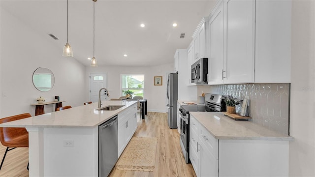 803 Allison Pl, Bartow, FL 33830 - kitchen featuring stainless steel appliances, light wood-type flooring, a center island with sink, white cabinetry, and a breakfast bar