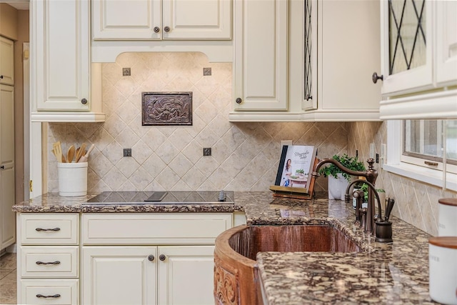 3906 Canyon Lake Pt, Lakeland, FL 33813 - kitchen with a sink, black electric stovetop, dark stone countertops, backsplash, and white cabinets