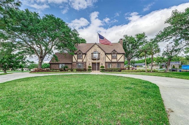3906 Canyon Lake Pt, Lakeland, FL 33813 - tudor-style house featuring a chimney, a front yard, and curved driveway