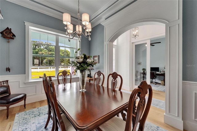 9004 Selph Rd, Lakeland, FL 33810 - dining area with arched walkways, ornamental molding, a wainscoted wall, a chandelier, and light wood finished floors