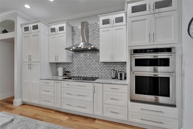 9004 Selph Rd, Lakeland, FL 33810 - kitchen with wall chimney range hood, double oven, crown molding, and black electric cooktop