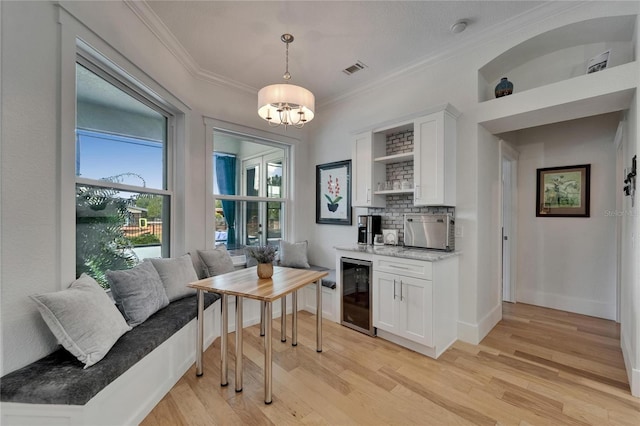 9004 Selph Rd, Lakeland, FL 33810 - bar with indoor wet bar, light wood-type flooring, ornamental molding, a chandelier, and beverage cooler