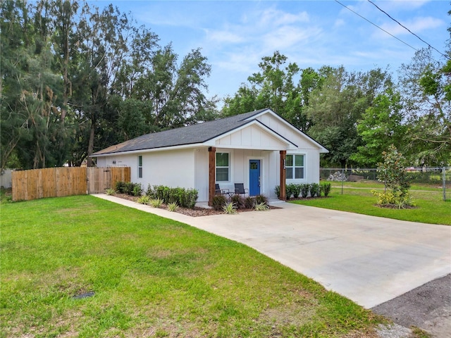 view of front of home featuring board and batten siding, a front yard, fence, and driveway