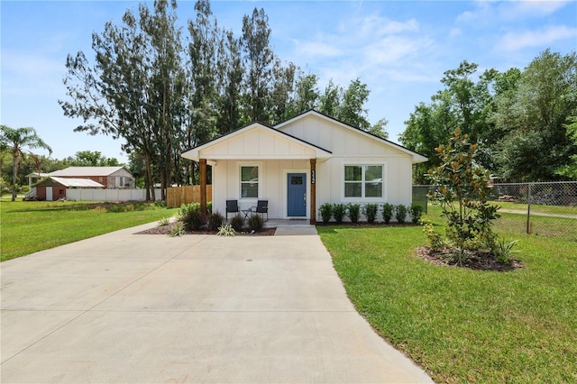view of front of property with driveway, fence, and a front lawn