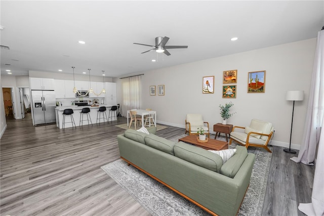 living area with wood finished floors, baseboards, a ceiling fan, and recessed lighting