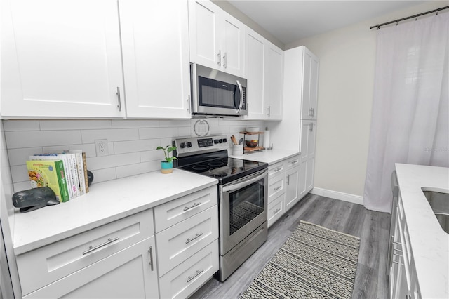 kitchen featuring white cabinetry, tasteful backsplash, light wood-style flooring, and appliances with stainless steel finishes