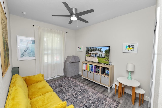 living room featuring baseboards, a ceiling fan, and wood finished floors