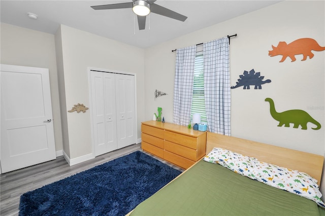 bedroom featuring wood finished floors, a closet, a ceiling fan, and baseboards