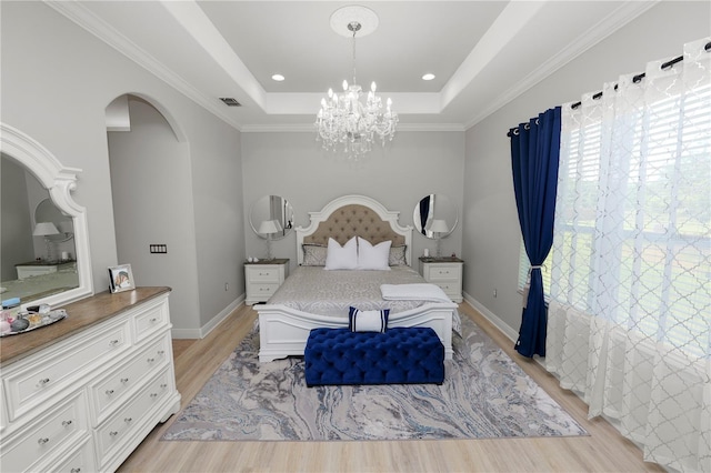 bedroom featuring light wood finished floors, arched walkways, a chandelier, a raised ceiling, and crown molding