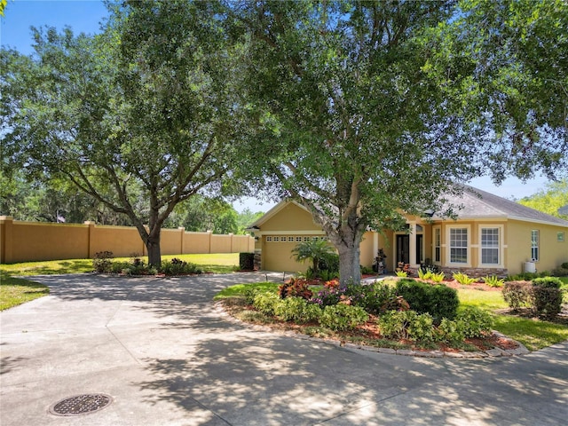 view of front facade with driveway, fence, stucco siding, a garage, and stone siding