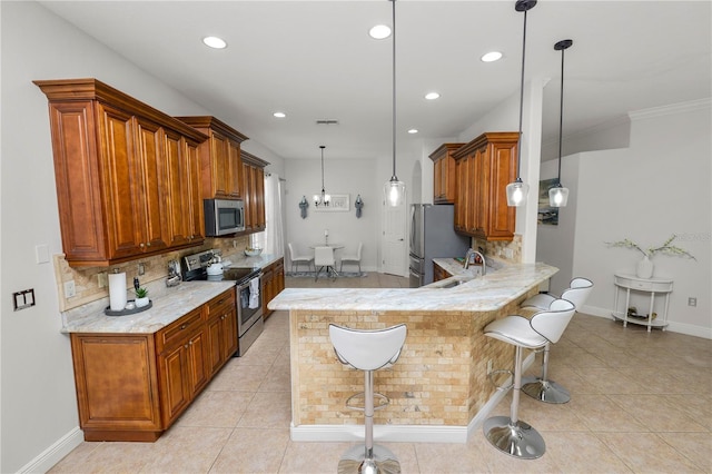 kitchen with appliances with stainless steel finishes, tasteful backsplash, a sink, brown cabinetry, and a peninsula