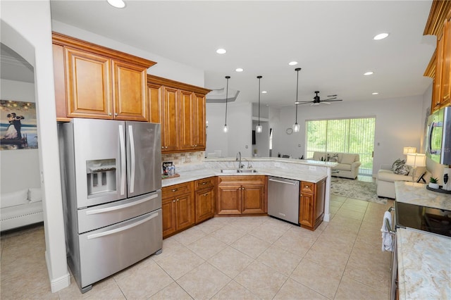 kitchen featuring stainless steel appliances, a sink, ceiling fan, open floor plan, and brown cabinetry