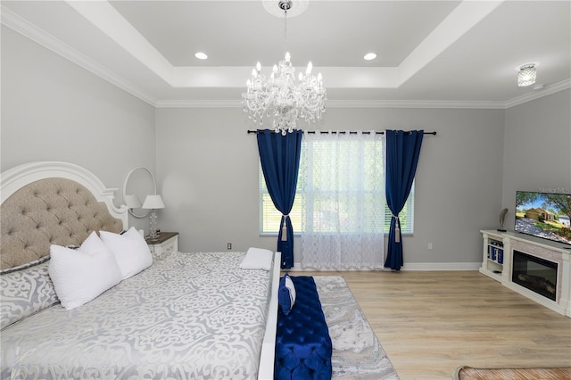 bedroom with wood finished floors, a chandelier, a tray ceiling, crown molding, and baseboards