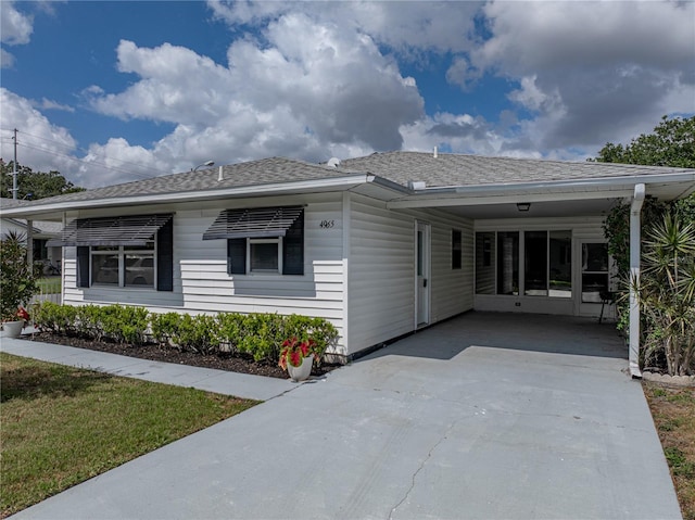 view of front of home with roof with shingles, a carport, and driveway
