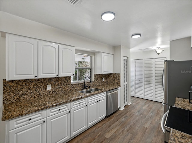 kitchen featuring a sink, stainless steel appliances, dark wood finished floors, backsplash, and white cabinets