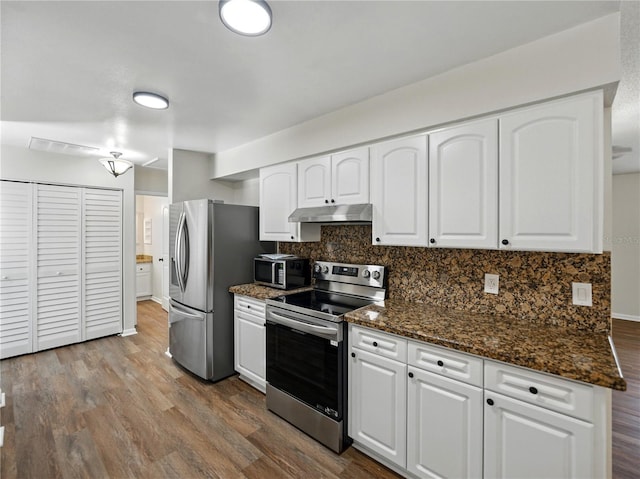 kitchen with under cabinet range hood, appliances with stainless steel finishes, decorative backsplash, and white cabinets