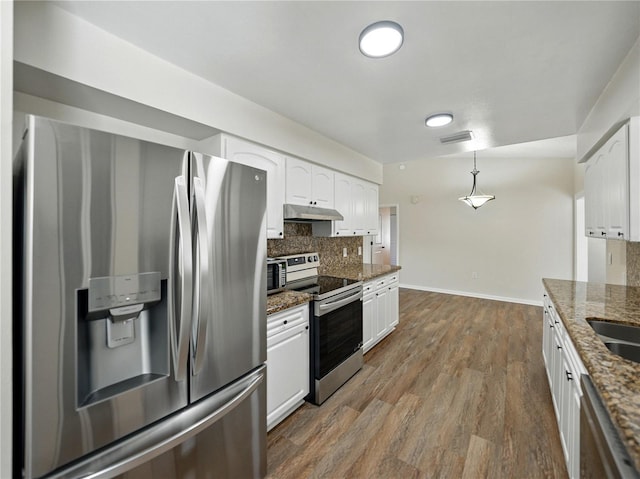 kitchen with under cabinet range hood, stainless steel appliances, baseboards, and white cabinets
