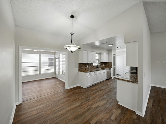 kitchen with a sink, dishwasher, vaulted ceiling, white cabinetry, and baseboards