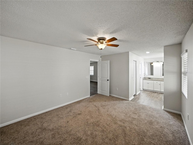 interior space with ensuite bath, a textured ceiling, carpet, and baseboards