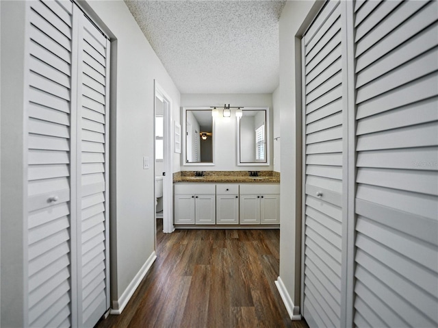 full bath with a sink, toilet, a closet, and wood finished floors