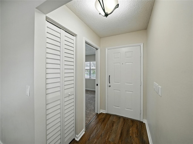 hallway with baseboards, dark wood finished floors, and a textured ceiling
