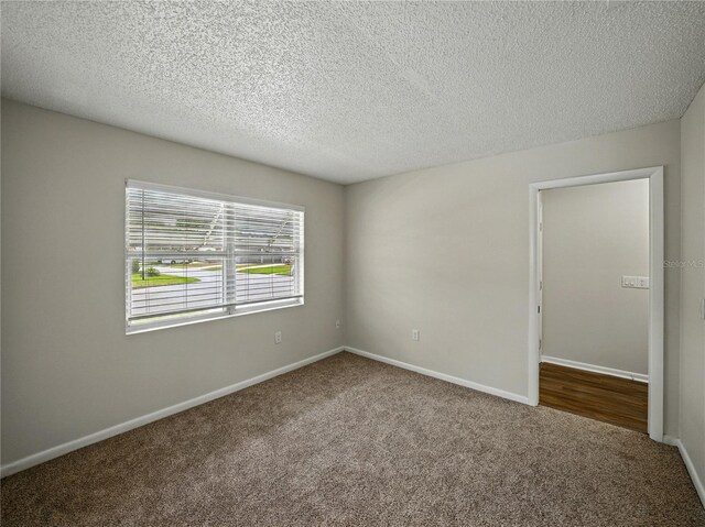 spare room featuring carpet, a textured ceiling, and baseboards