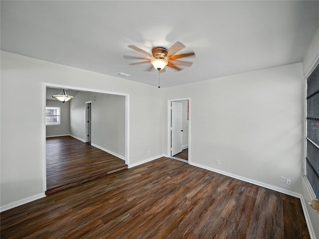 empty room with baseboards, ceiling fan, dark wood finished floors, and visible vents