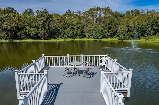 view of dock with a wooded view and a water view