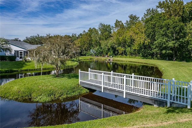 dock area with a yard, fence, and a water view