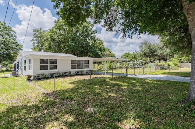 exterior space featuring concrete driveway, a fenced front yard, central AC unit, a yard, and a gate