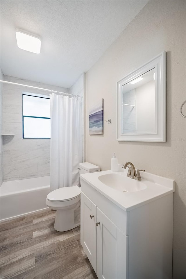 full bathroom featuring a textured ceiling, vanity, toilet, wood finished floors, and shower / bath combo with shower curtain