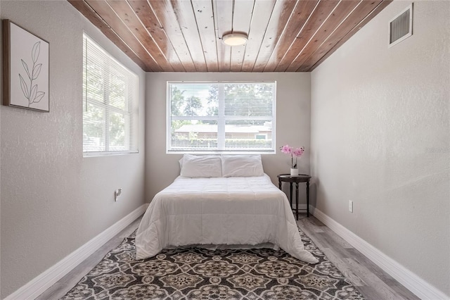 bedroom with light wood-style floors, visible vents, wood ceiling, a textured wall, and baseboards