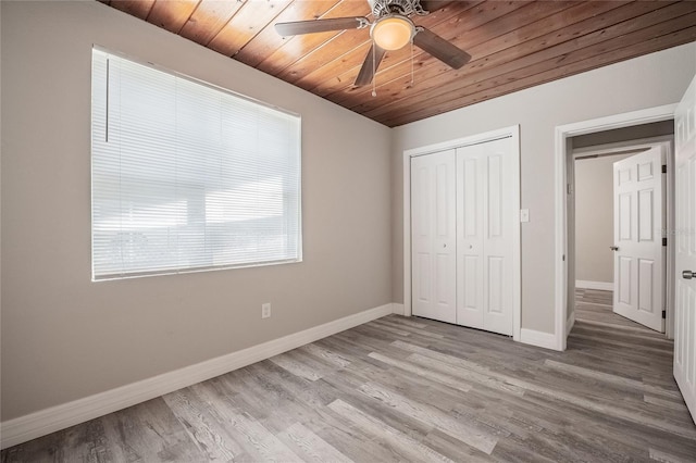 unfurnished bedroom featuring a closet, baseboards, wooden ceiling, ceiling fan, and light wood-style flooring