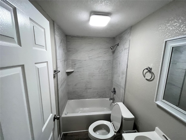full bath with washtub / shower combination, toilet, and a textured ceiling