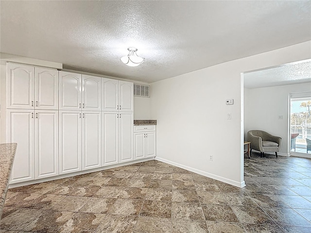 4921 Marlin Dr, New Port Richey, FL 34652 - interior space featuring a textured ceiling, stone finish flooring, baseboards, and visible vents