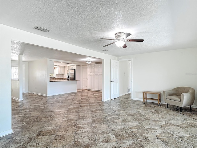 4921 Marlin Dr, New Port Richey, FL 34652 - unfurnished living room featuring visible vents, baseboards, a ceiling fan, and a textured ceiling