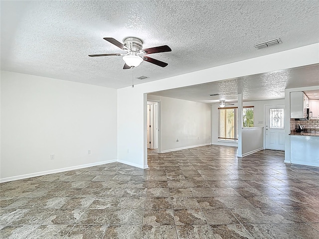 4921 Marlin Dr, New Port Richey, FL 34652 - unfurnished living room with visible vents, baseboards, a ceiling fan, and a textured ceiling
