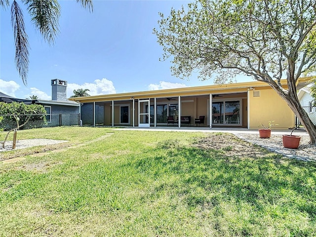 4921 Marlin Dr, New Port Richey, FL 34652 - back of house with ceiling fan, a sunroom, stucco siding, a lawn, and fence