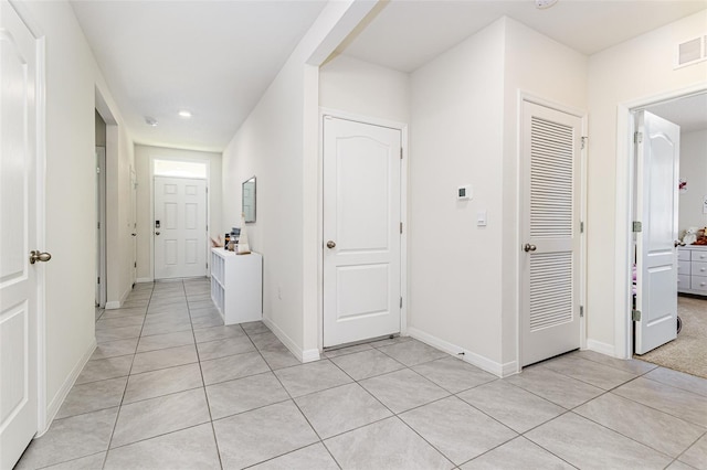 hallway featuring baseboards, recessed lighting, and light tile patterned flooring