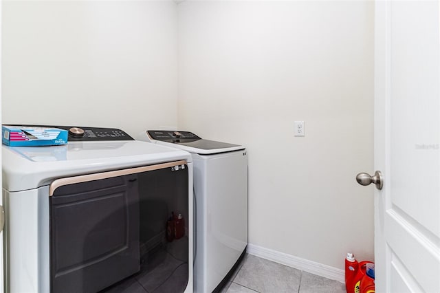 laundry area with separate washer and dryer, baseboards, laundry area, and light tile patterned floors