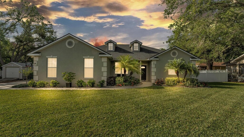 660 W Cummings St, Lake Alfred, FL 33850 - view of front of house with a garage, stucco siding, fence, and a lawn