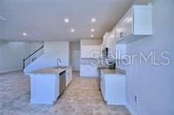 kitchen with recessed lighting, light countertops, white cabinets, and a center island with sink