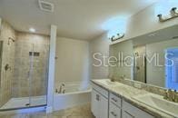 bathroom with a sink, double vanity, visible vents, a bath, and a stall shower