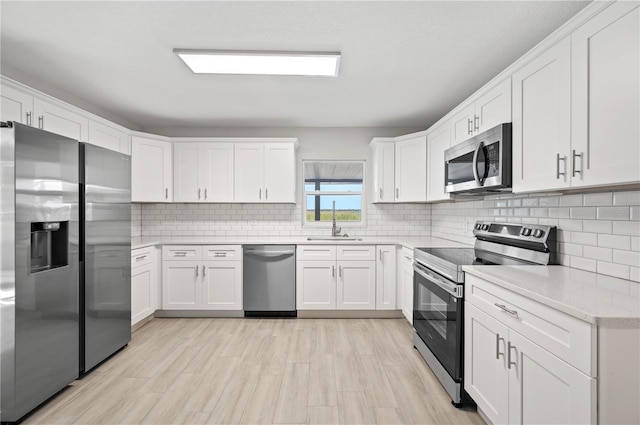 1502 Edgewater Beach Dr, Lakeland, FL 33805 - kitchen with white cabinetry, backsplash, stainless steel appliances, light wood finished floors, and a sink